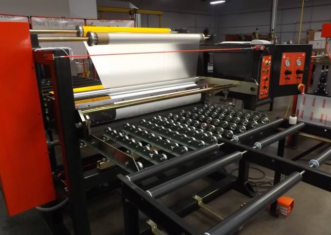 Industrial Laminator Walco 822 - close-up of the film unwind station and protective film being fed through the application rollers