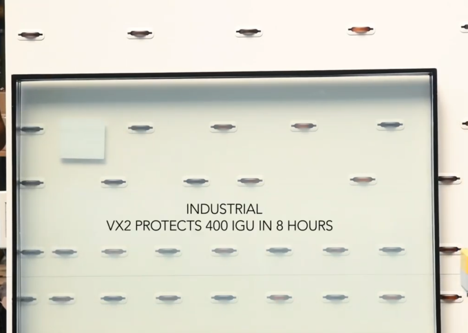 Pelliculeuse verticale industrielle VX2 par Walco - détail du texte "VX2 protège 400 IGU en 8 heures" sur vitre.